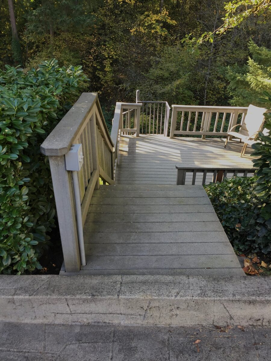 Weathered wooden deck stairs with grey pressure-treated railing before rebuild