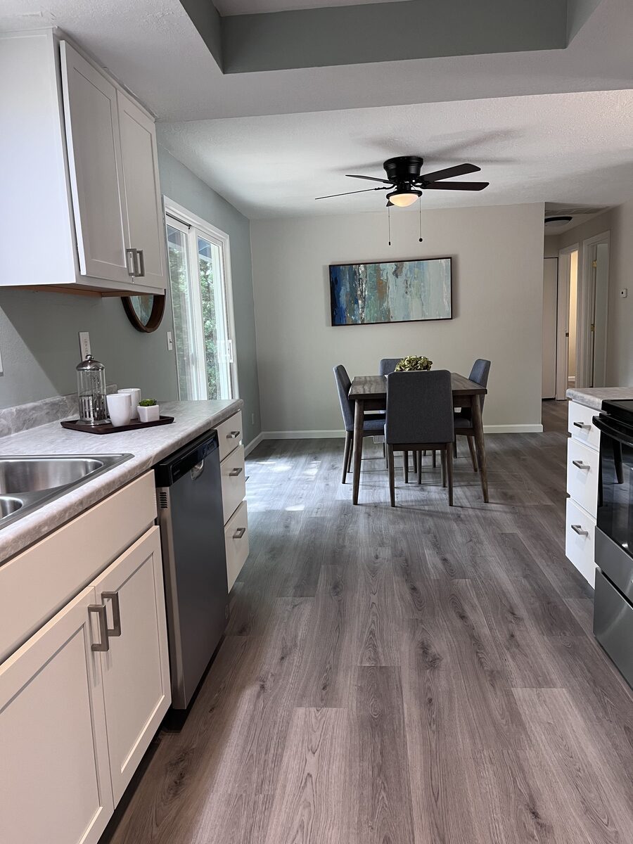Finished kitchen and dining area with grey plank flooring and white cabinetry