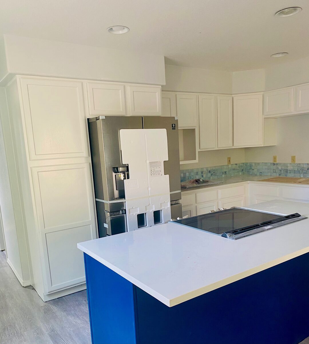 Kitchen remodel in progress with white cabinets and a navy blue island