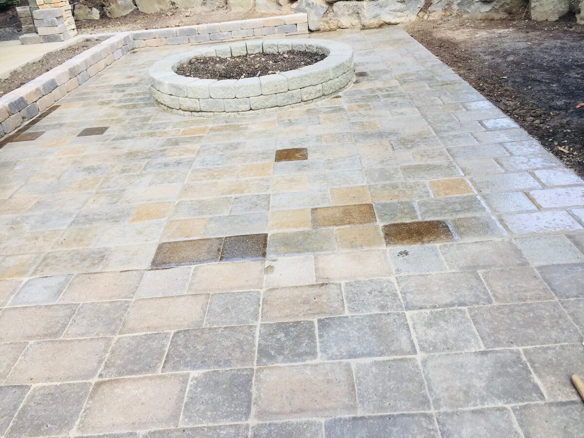 Finished multi-tone paver patio with a circular stone fire pit surround