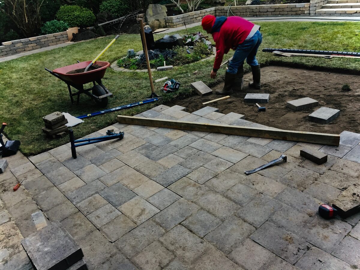 Crew member setting pavers on a compacted base during installation